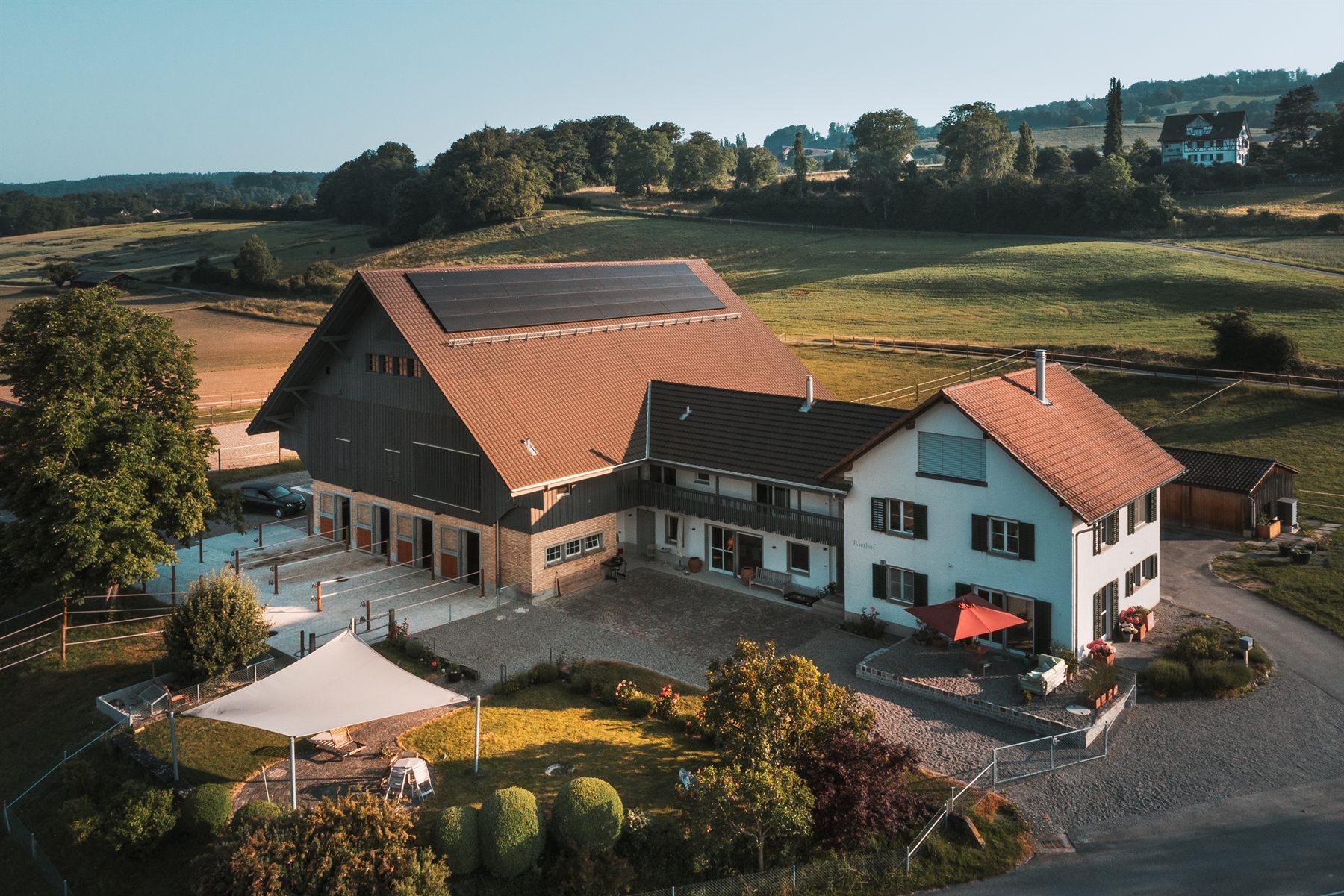 Luftaufnahme des Riethofs im Abendlicht – Hof, Garten und Weiden